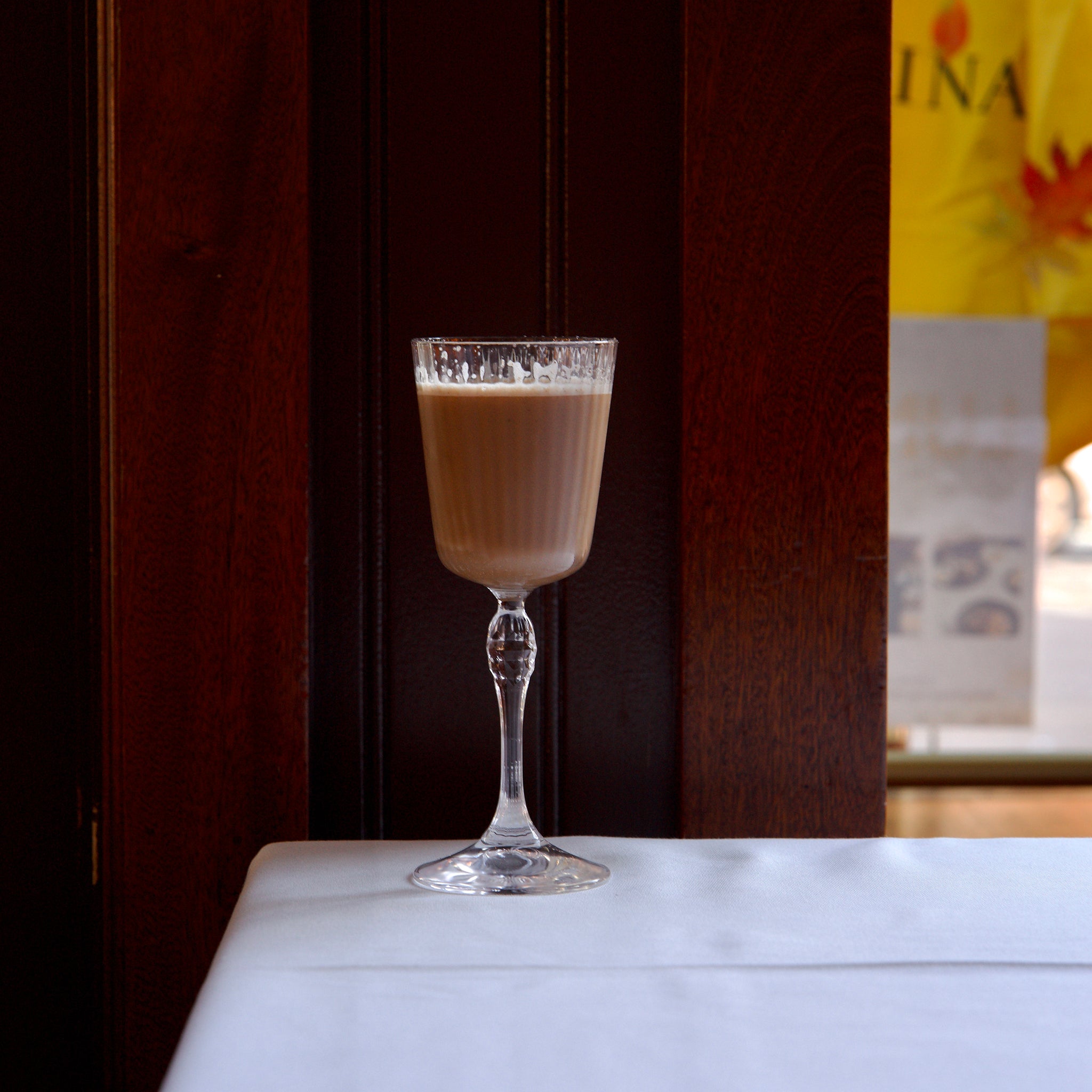 Glass of fall cocktail on a white surface with a blurred background