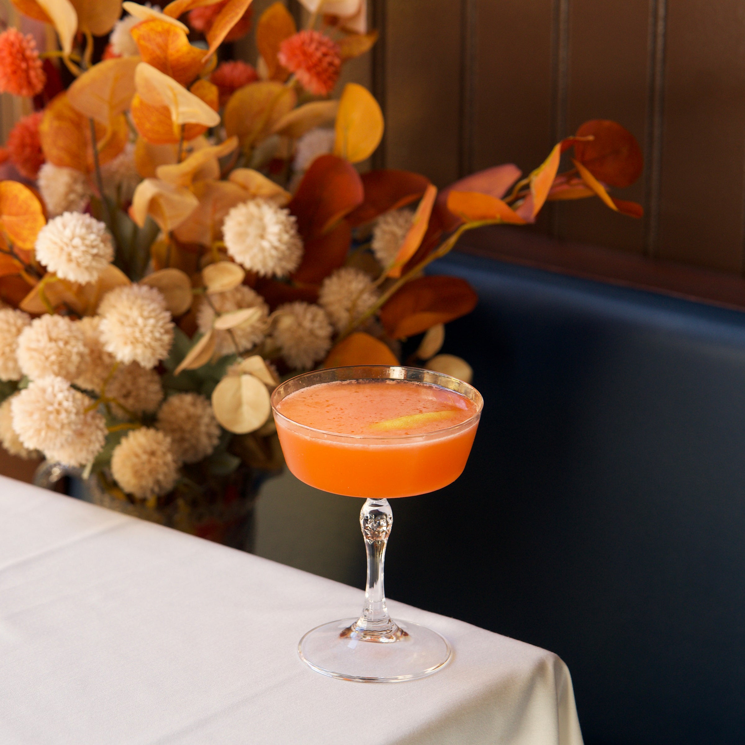 Cocktail in a glass with decorative flowers in the background