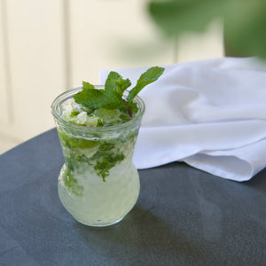 Glass with Mojito cocktail with mint leaves on a dark surface with a white napkin.