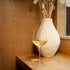InAlto Uno Medium wine glass with white wine and a decorative vase on a wooden surface