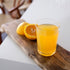 Glass of orange juice on a wooden board with oranges in the background