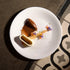 Delicate dessert presentation on a white plate with a dark background